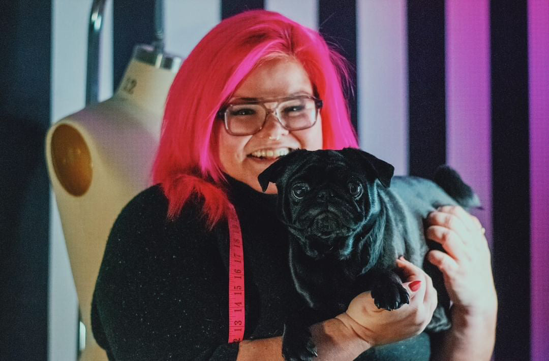 The designer behind Virtue & Valour holding their dog.