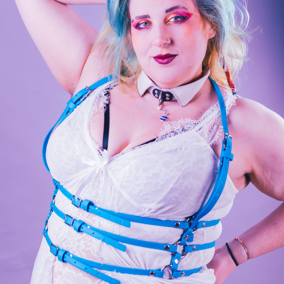 Woman wearing a turquoise suspender harness over a white negligee.