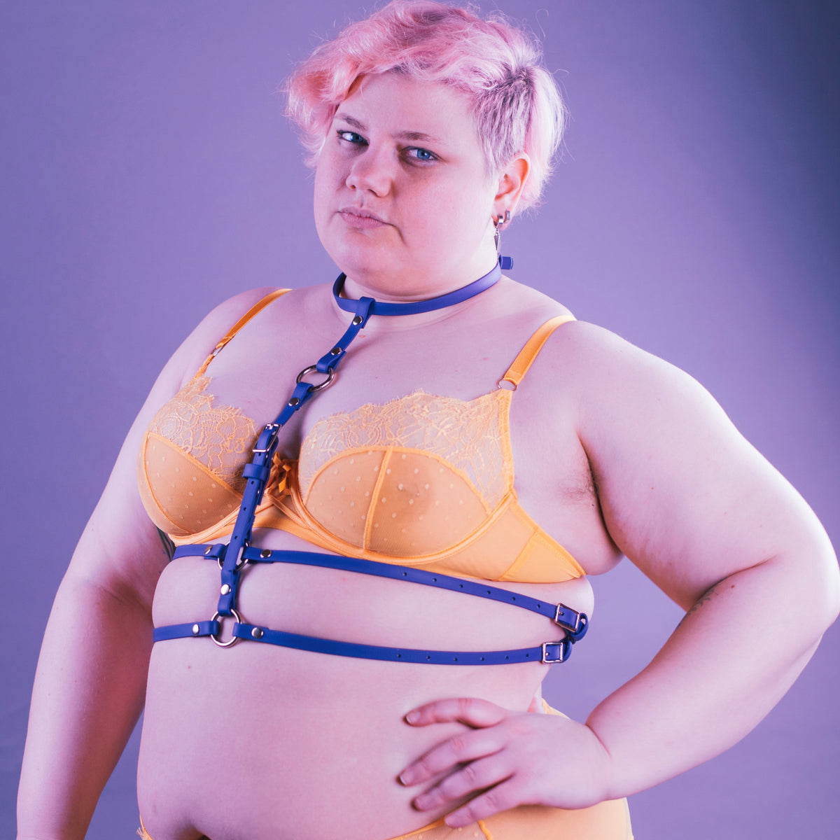 Woman wearing yellow lingerie and a purple harness.