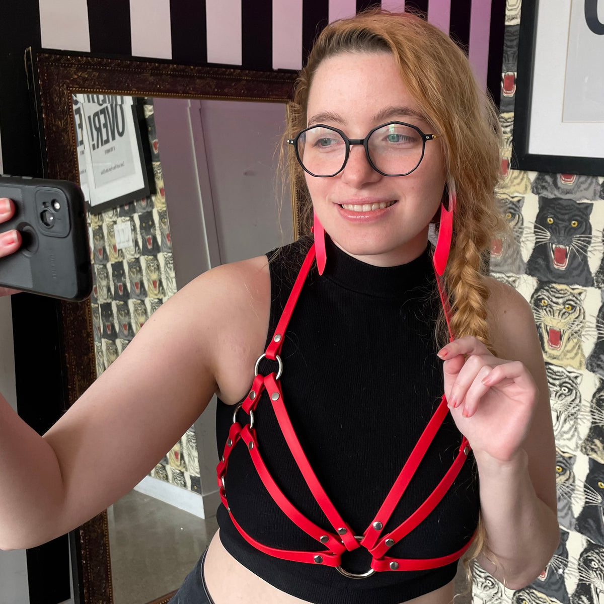 Woman wearing a red harness top outfit taking a selfie.