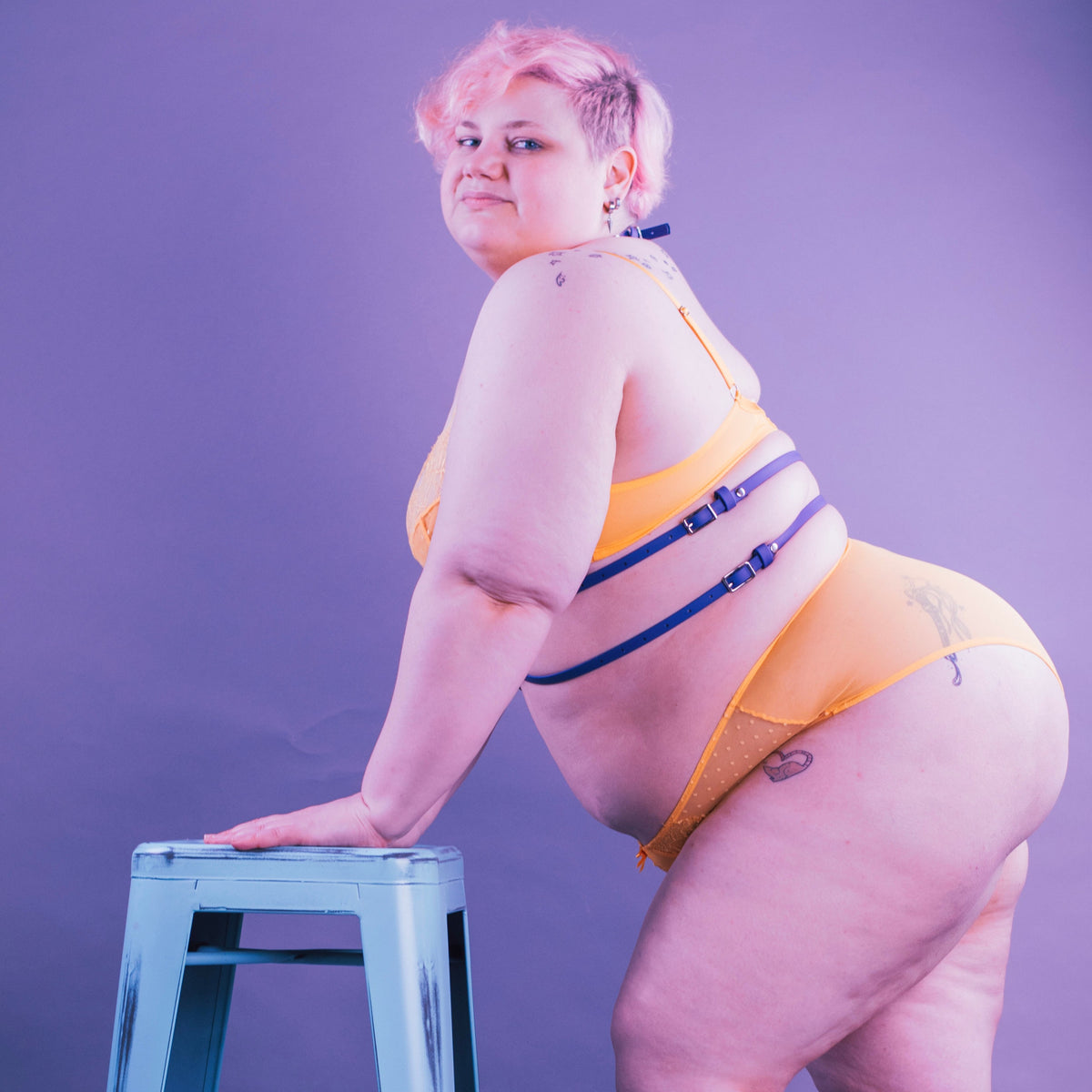 Person wearing yellow lingerie and a purple vegan harness.