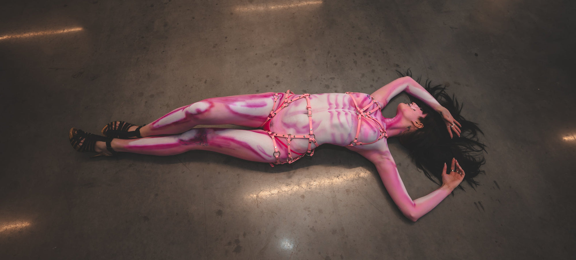 Person wearing a pink and white outfit with gold accents lying on a reflective floor.