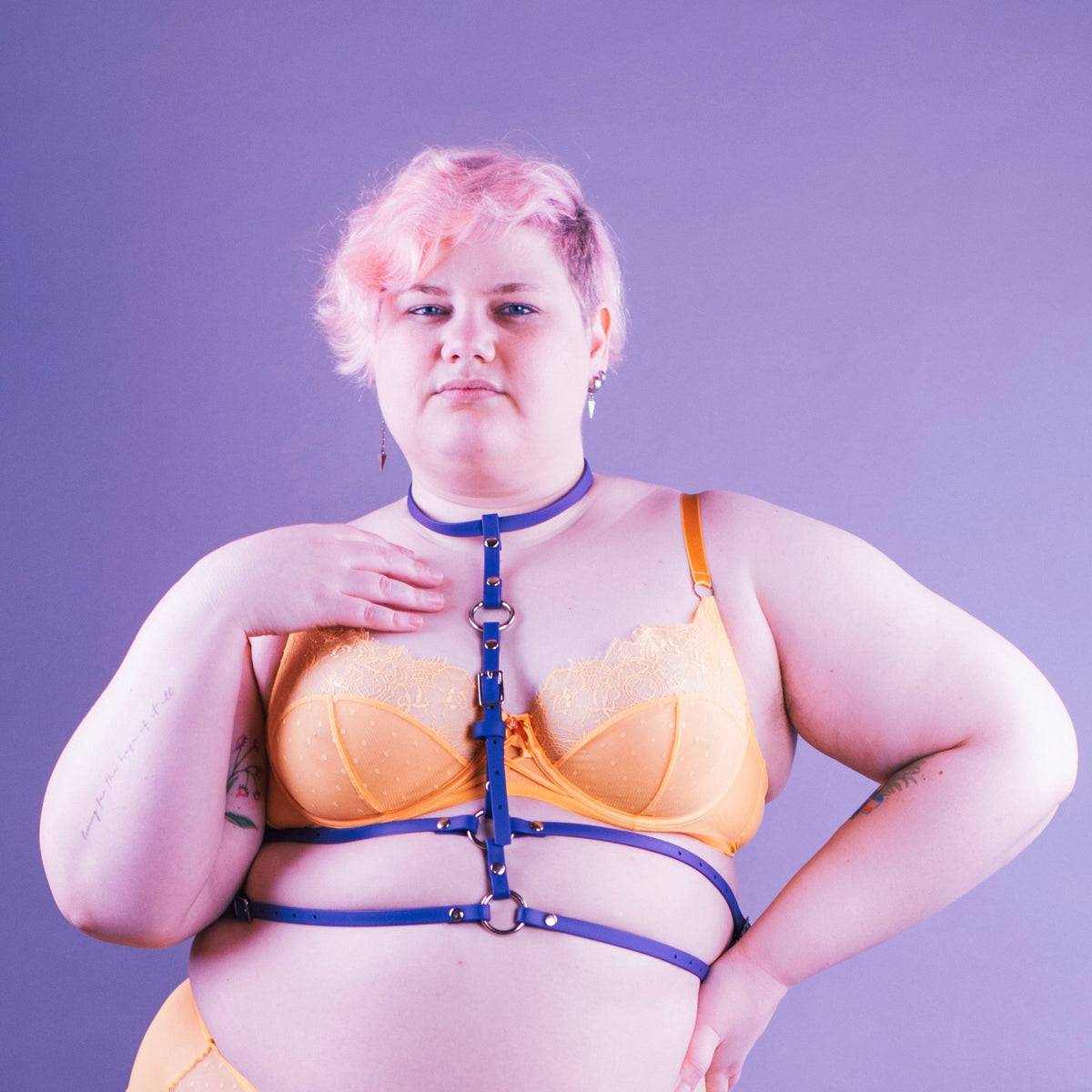 Woman wearing yellow lingerie and a purple waist harness.