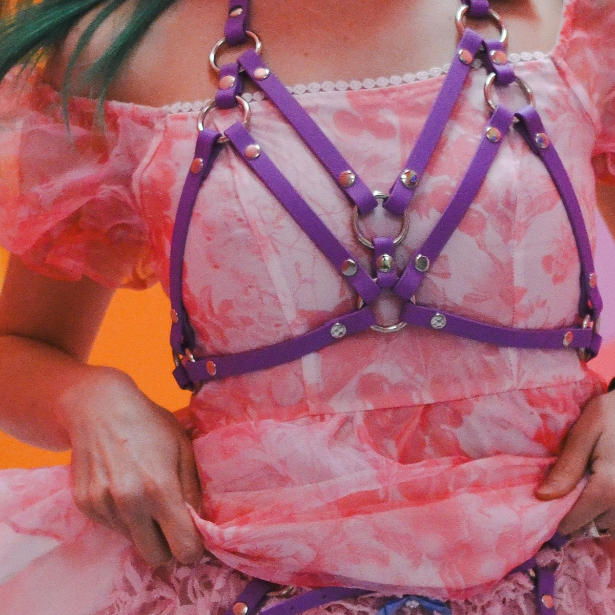 Closeup of a woman wearing pink with a purple bra top on top.