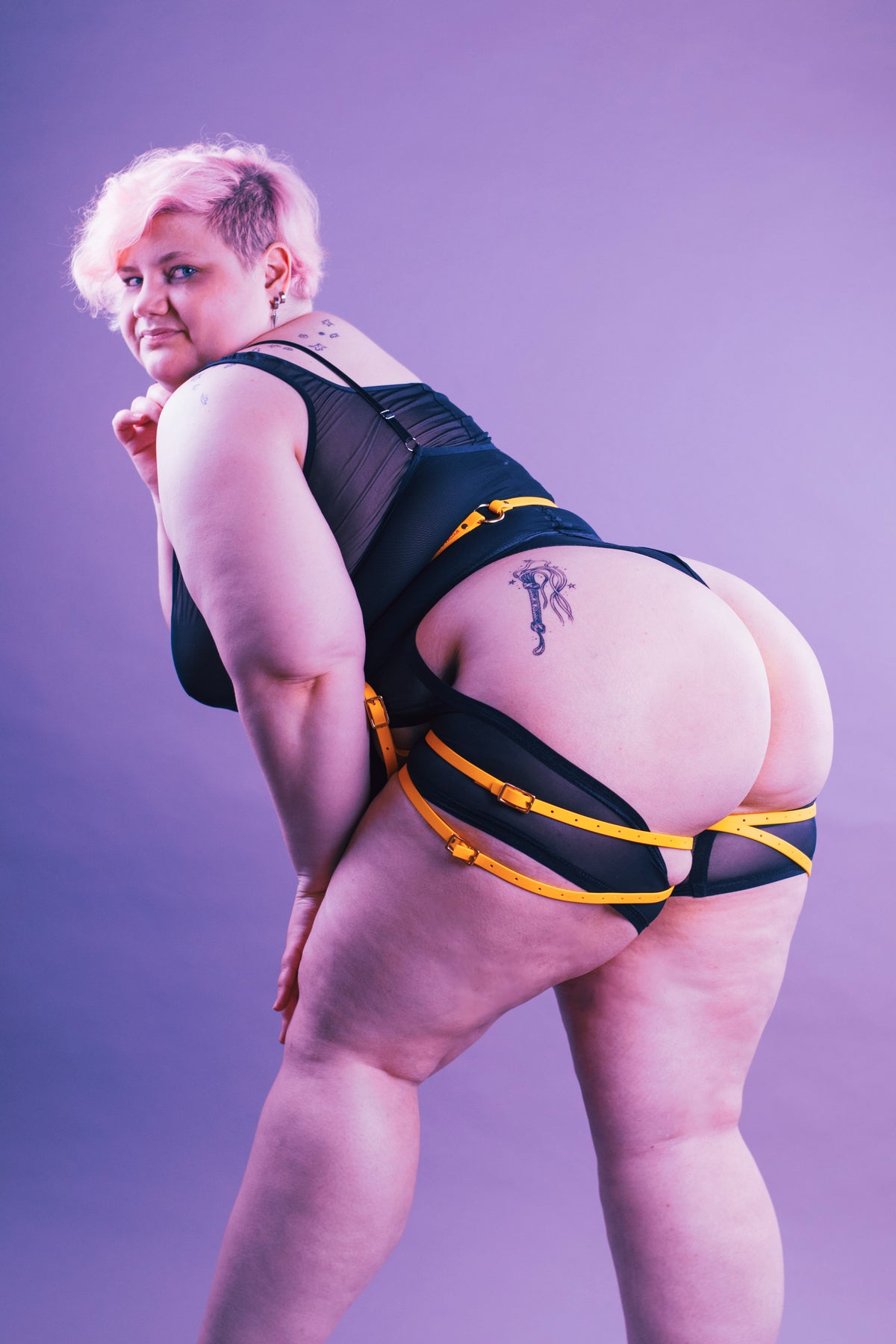 Woman in black lingerie and a yellow classic thigh harness.