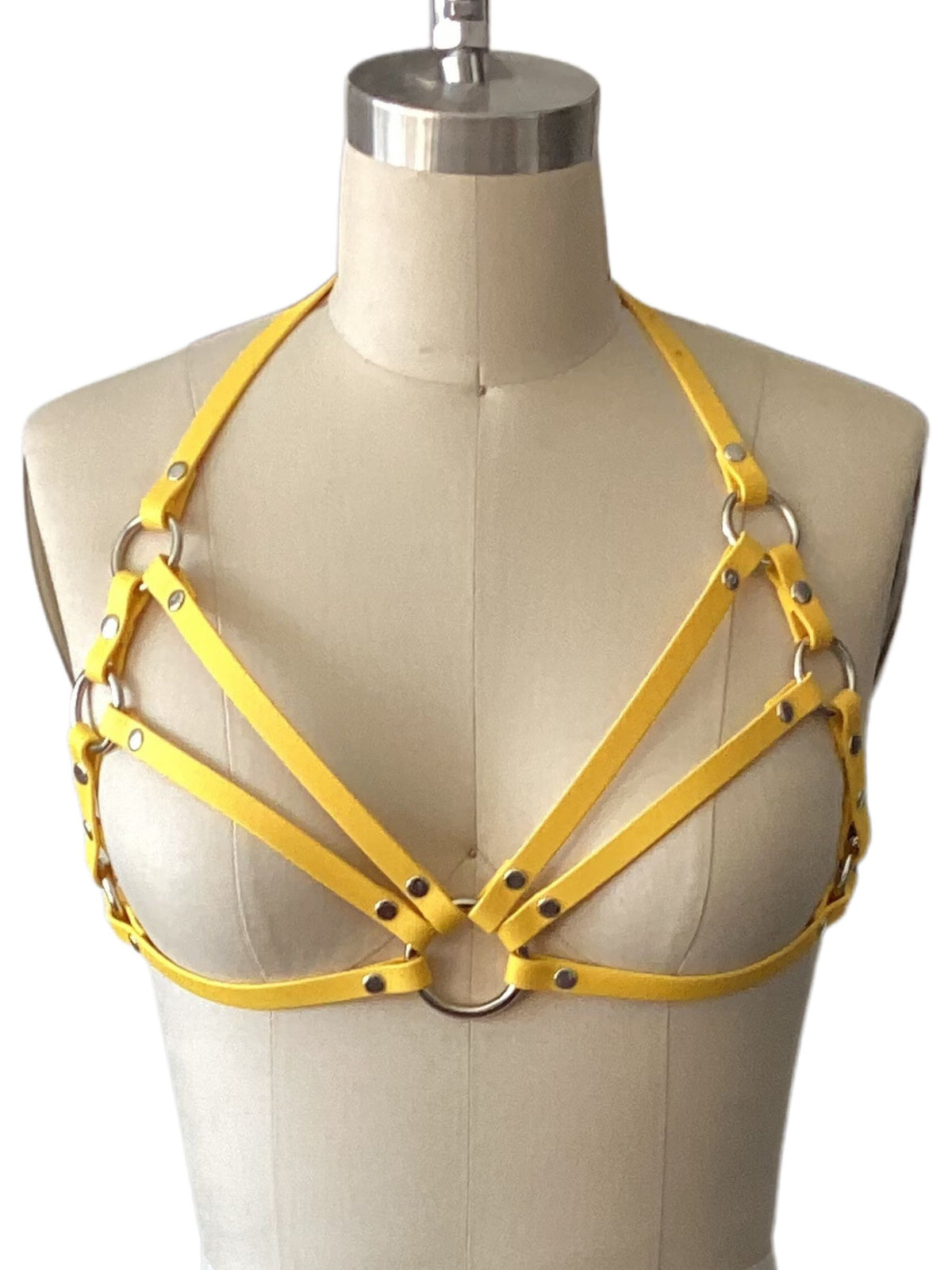 a photo of a yellow caged chest harness for women on a dress form on a white background